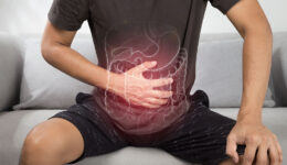 A Man Sitting on a Couch Holding His Stomach With an Illustration of Internal Digestive Organs Symptoms of Digestive Issues