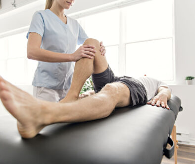 A Sports Medicine Doctor Holding an Athlete’s Knee Lying Down on a Massage Table